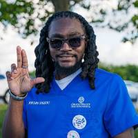 Man in nursing student scrubs, smiling and "anchoring up"